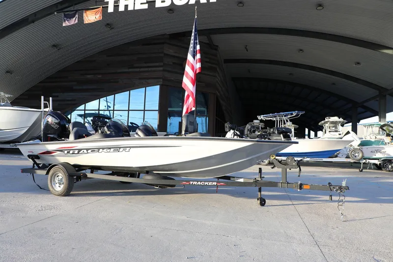 Slide: The Image of 2024 Bass Tracker Pro 19 boat on trailer, displayed outdoors with American flag. - 13