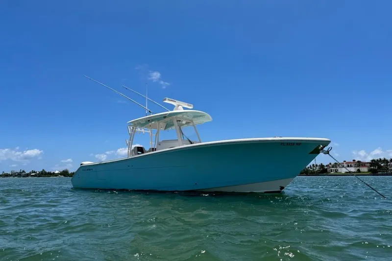 The Image of 2018 Cobia 320 Center Console boat anchored on calm water under clear blue sky. - 0