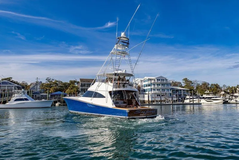 Slide: The Image of 2022 Viking 72 Convertible yacht cruising in a scenic marina under a clear blue sky. - 10