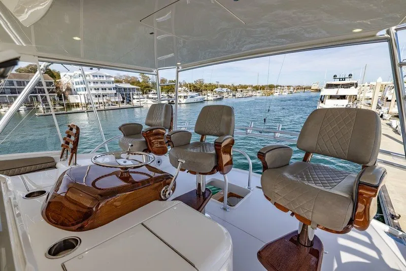 Slide: The Image of Luxurious 2022 Viking 72 Convertible yacht interior with plush seating and scenic marina view. - 18
