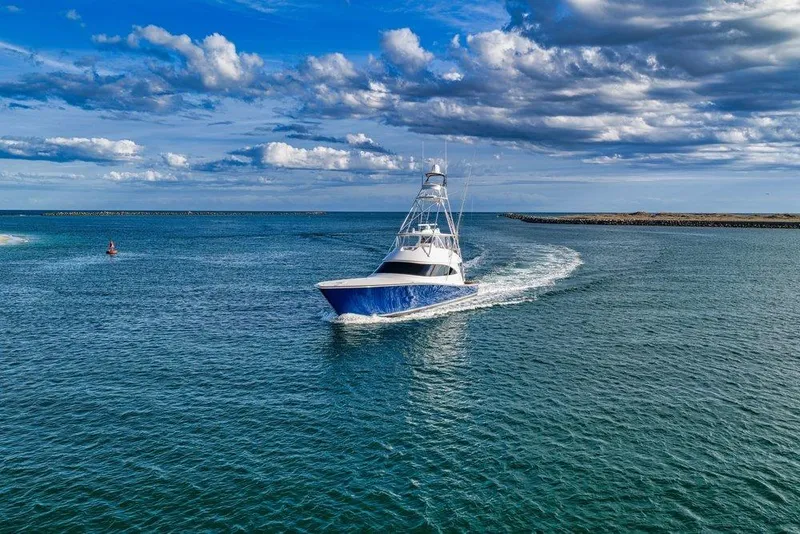 Slide: The Image of 2022 Viking 72 Convertible yacht cruising on open water under a partly cloudy sky. - 2