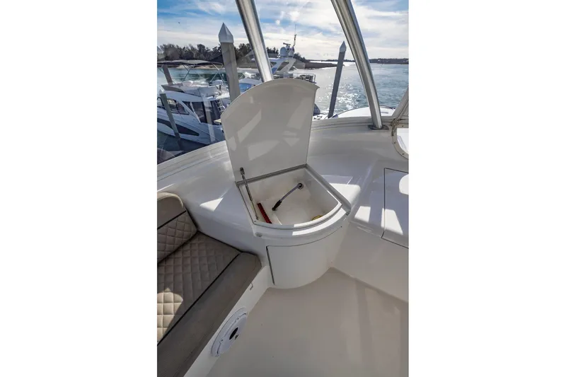 Slide: The Image of 2022 Viking 72 Convertible yacht interior with open storage compartment and cushioned seating. - 22