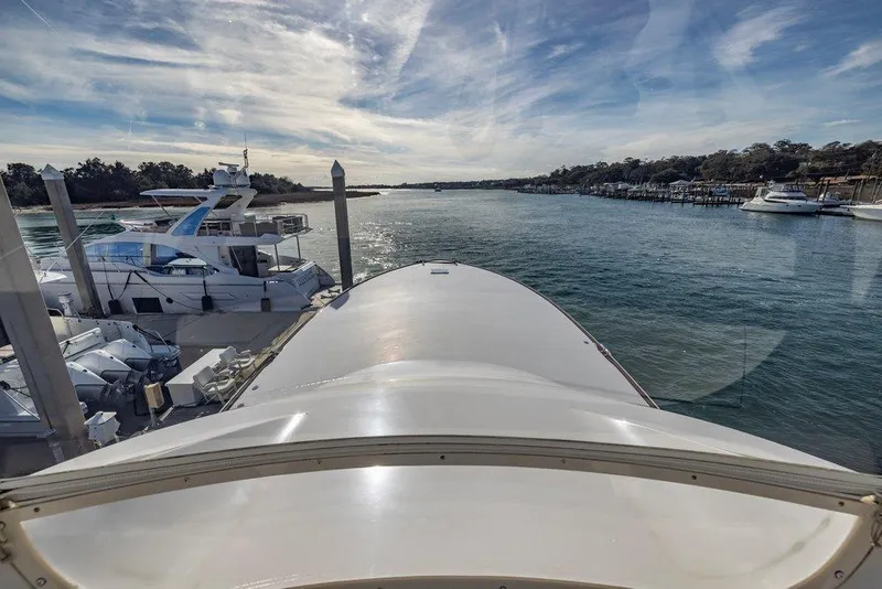 Slide: The Image of View from 2022 Viking 72 Convertible yacht, overlooking marina and waterway under a partly cloudy sky. - 24