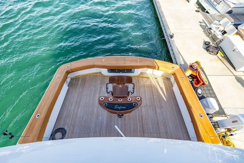 Slide: The Image of 2022 Viking 72 Convertible yacht deck with wooden finish, docked by the water. - 26