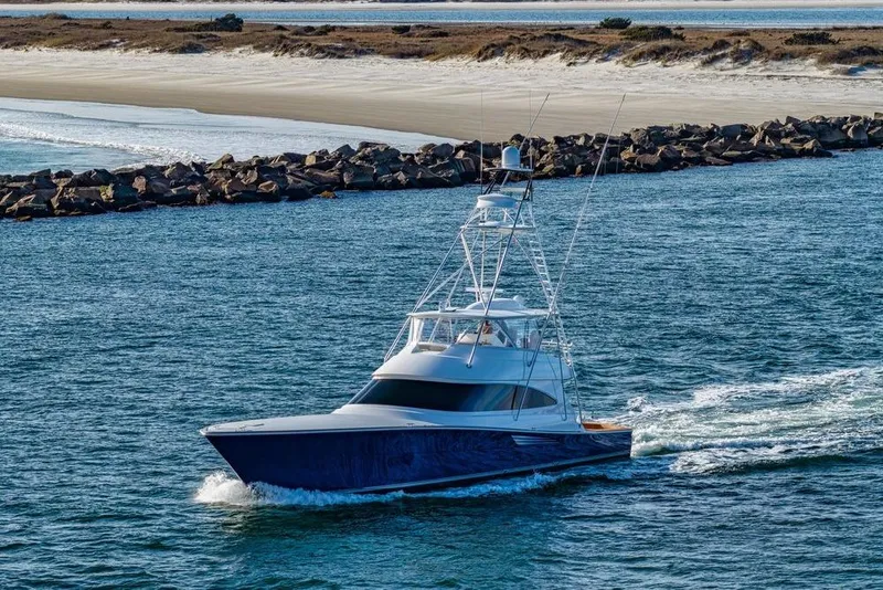 Slide: The Image of 2022 Viking 72 Convertible yacht cruising near rocky shoreline. - 7