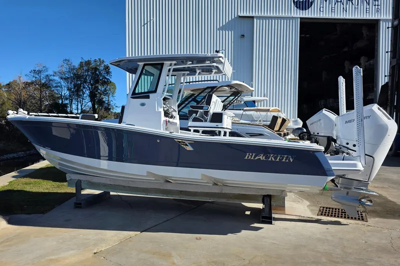 Slide: The Image of 2026 Blackfin 262 HB boat with dual Mercury engines, docked outside a marine center. - 2