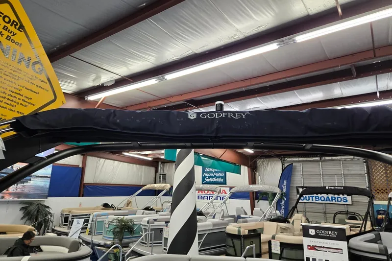 Slide: The Image of 2026 Godfrey Monaco 235 QSB pontoon boat displayed in showroom with promotional banners. - 31