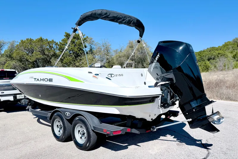 Slide: The Image of 2023 Tahoe 2150 boat on trailer with outboard motor, parked outdoors. - 11