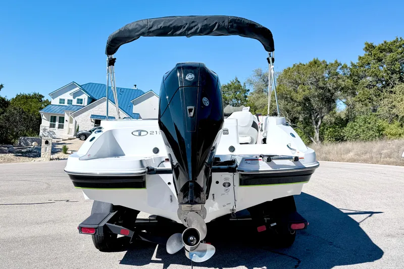 Slide: The Image of 2023 Tahoe 2150 boat with outboard motor, parked on a sunny residential street. - 12