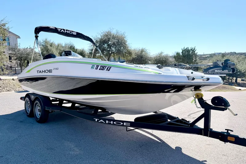 Slide: The Image of 2023 Tahoe 2150 boat on trailer, parked outdoors under clear blue sky. - 15