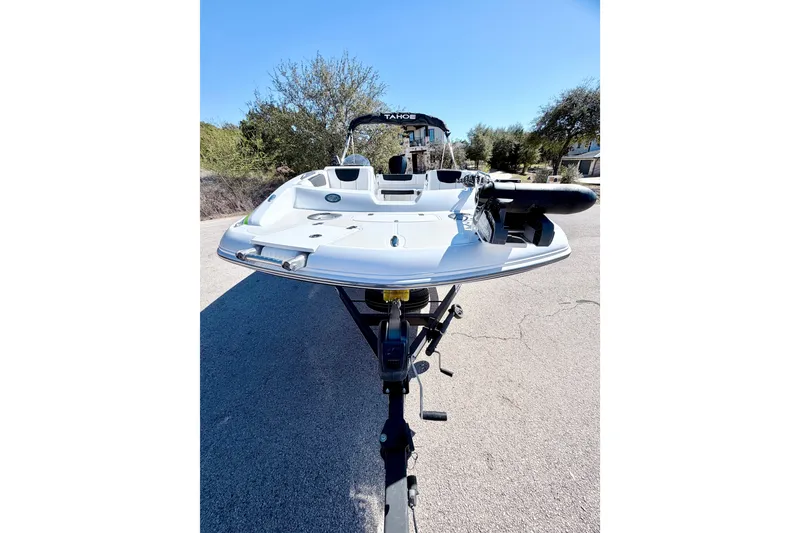 Slide: The Image of 2023 Tahoe 2150 boat on trailer, parked on a sunny road with trees in background. - 16