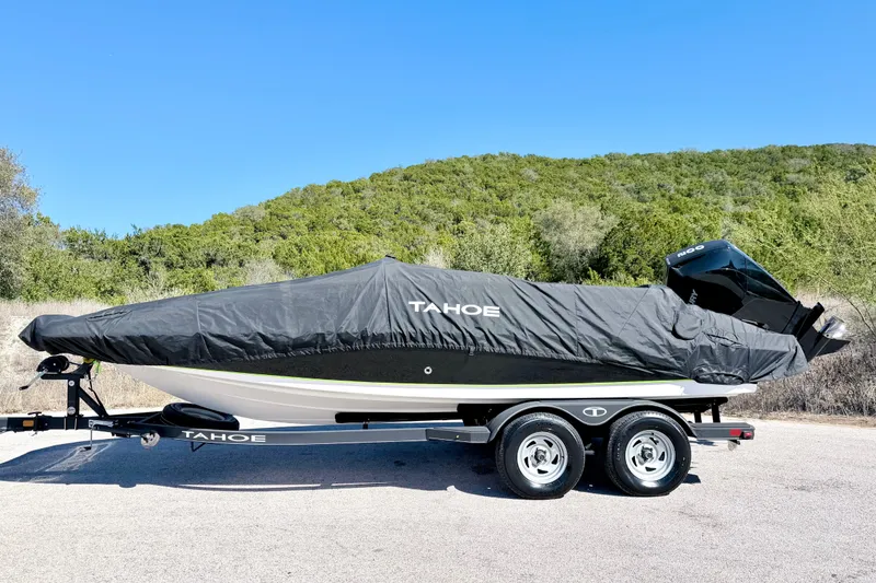 Slide: The Image of 2023 Tahoe 2150 boat covered on trailer, parked outdoors with scenic background. - 17