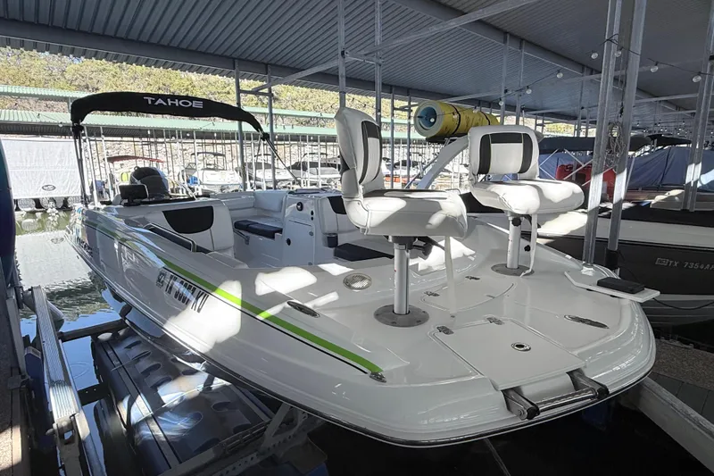 Slide: The Image of 2023 Tahoe 2150 boat docked in a covered marina, featuring sleek design and seating. - 20