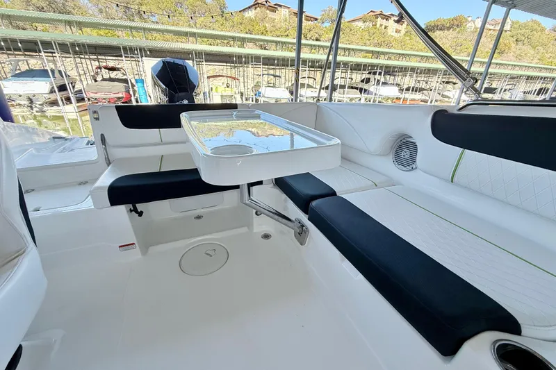 Slide: The Image of 2023 Tahoe 2150 boat interior with seating and table, docked at marina. - 28
