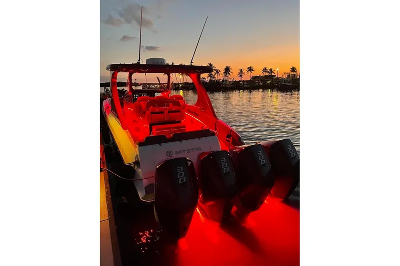 Slide: The Image of 2021 Mystic Powerboats M3800 illuminated at sunset with palm trees in the background. - 9