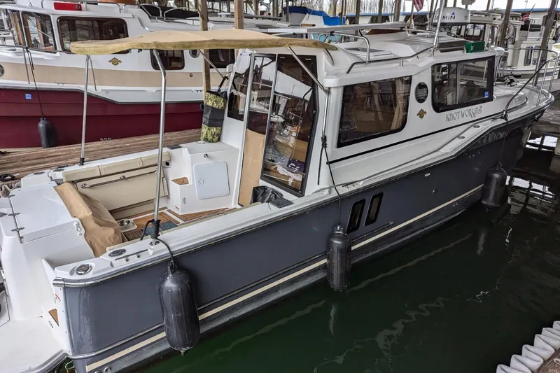 Slide: The Image of 2020 Ranger Tugs R-27 boat docked in marina, featuring spacious deck and modern design. - 2