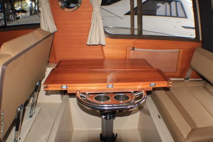 Slide: The Image of 2020 Ranger Tugs R-27 interior with wooden table, cup holders, and beige seating. - 62