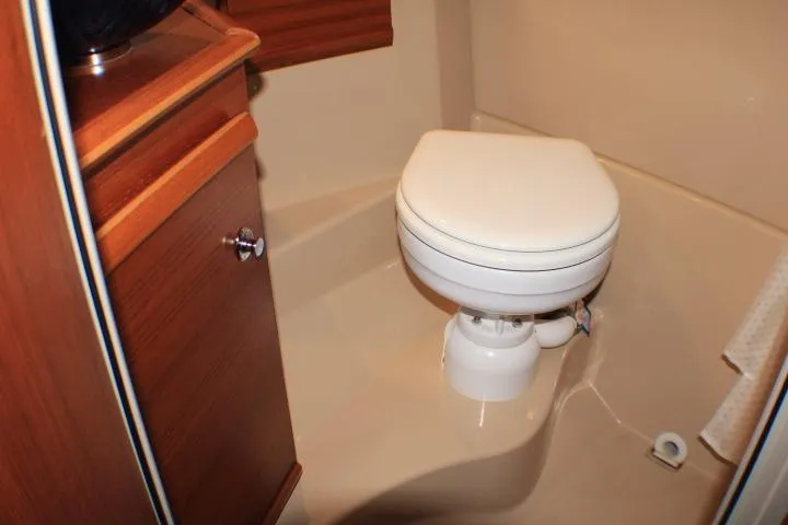 Slide: The Image of 2020 Ranger Tugs R-27 boat bathroom with compact toilet and wooden cabinetry. - 87