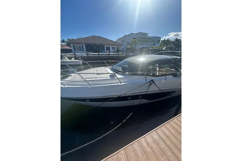 Slide: The Image of 2023 Schaefer 400 yacht docked under sunny skies, near waterfront homes. - 51