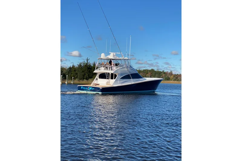 Slide: The Image of 2024 Viking 72 Convertible yacht cruising on a serene waterway under a clear blue sky. - 4