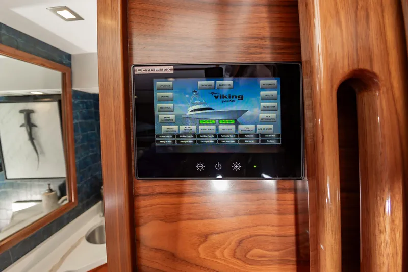 Slide: The Image of Touchscreen control panel on 2024 Viking 72 Convertible yacht, featuring sleek wood finish. - 54