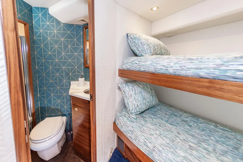 Slide: The Image of 2024 Viking 72 Convertible yacht interior with bunk beds and modern bathroom. - 79