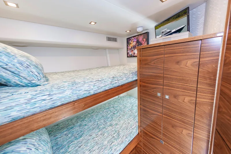 Slide: The Image of Luxurious 2024 Viking 72 Convertible yacht cabin with wooden cabinetry and cozy bunk beds. - 80