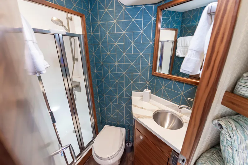 Slide: The Image of Luxurious bathroom in 2024 Viking 72 Convertible yacht with modern fixtures and geometric blue tiles. - 81