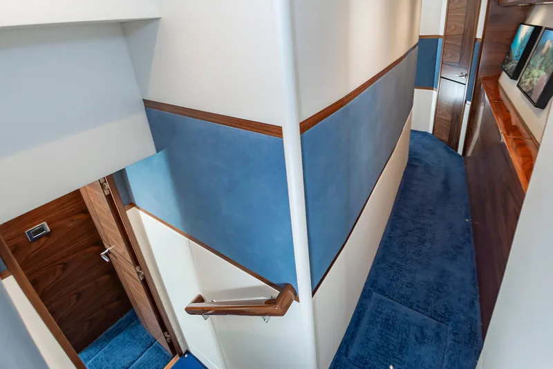 Slide: The Image of Luxurious hallway interior of 2024 Viking 72 Convertible yacht with blue carpet and wood accents. - 89