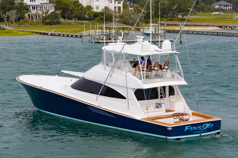 Slide: The Image of 2024 Viking 72 Convertible yacht cruising on water near coastal homes. - 9