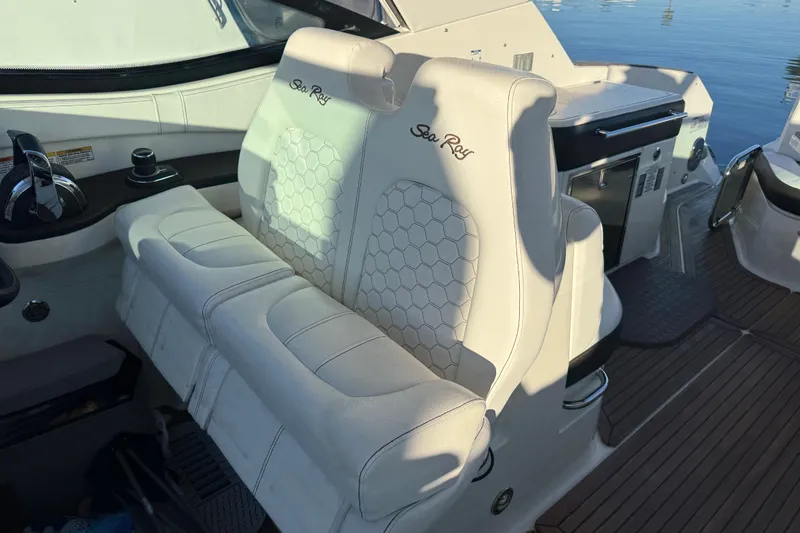 Slide: The Image of 2019 Sea Ray 320 Sundancer cockpit with white leather seating and control panel. - 13