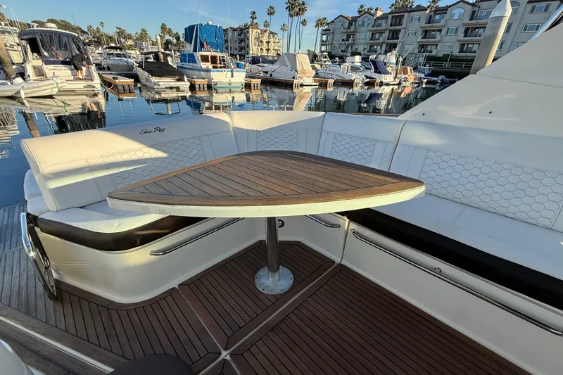 Slide: The Image of 2019 Sea Ray 320 Sundancer yacht with elegant seating and wooden table in marina setting. - 8