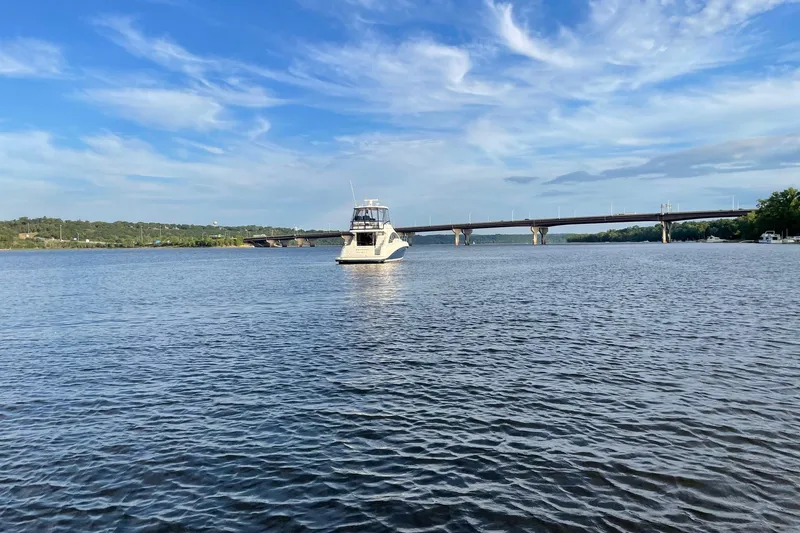 Slide: The Image of 2008 Sea Ray 47 Sedan Bridge yacht on a serene river with a bridge in the background. - 19