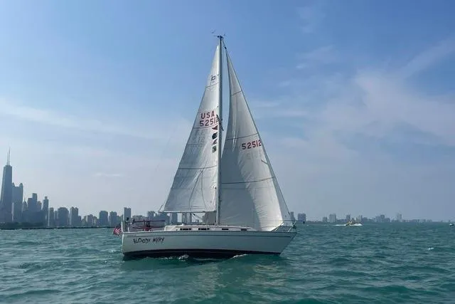 The Image of 1986 Pearson 303 sailboat on open water with city skyline in background. - 0