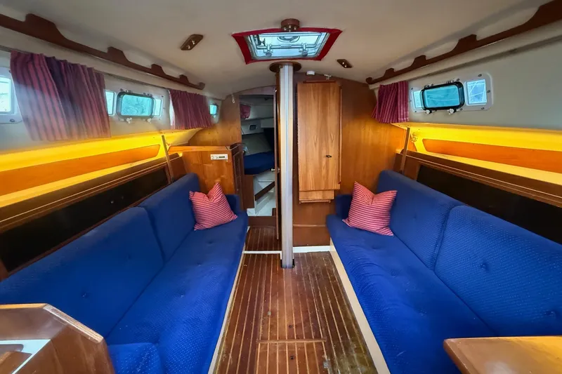 Slide: The Image of Interior of a 1986 Pearson 303 sailboat with blue seating and wooden accents. - 8
