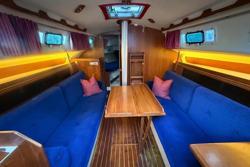 Slide: The Image of Interior of a 1986 Pearson 303 sailboat with blue seating and wooden table. - 9