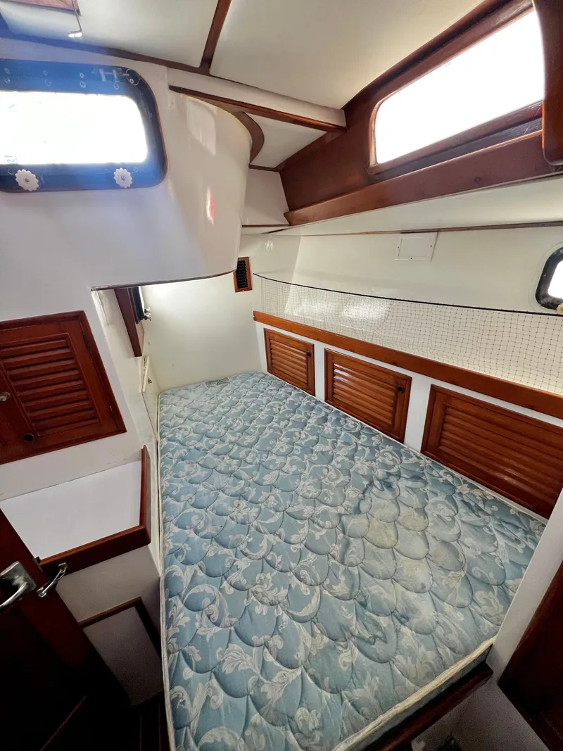 Slide: The Image of 1981 Cheoy Lee Golden Wave yacht cabin with bed, wooden accents, and windows. - 42