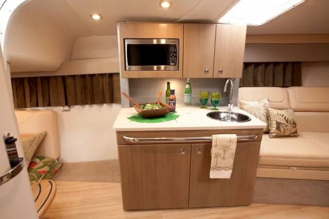 Slide: The Image of Manufacturer Provided Image: 2015 Formula 350 Sun Sport cabin kitchen with microwave, sink, and dining setup. - 27