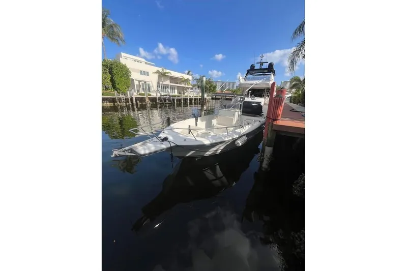 Slide: The Image of 1997 Stamas 290 Tarpon boat docked by waterfront homes under clear blue sky. - 3