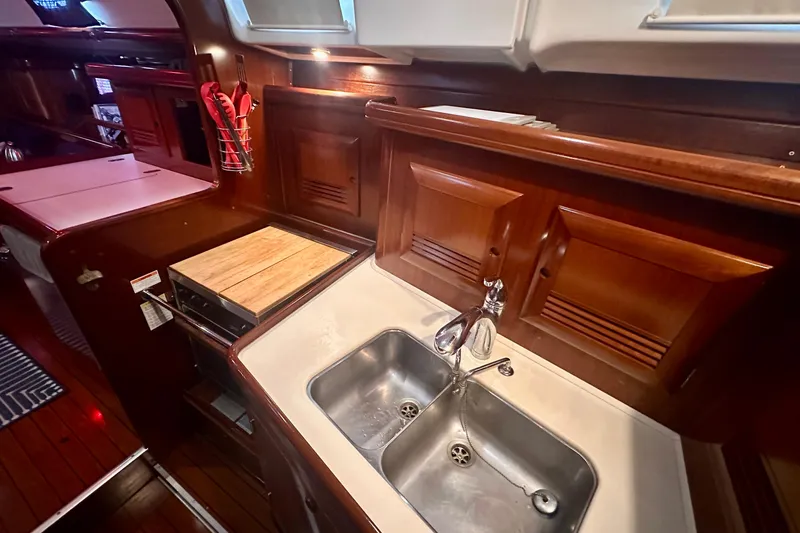 Slide: The Image of Luxurious 2004 Beneteau 50 yacht kitchen with wooden cabinetry and dual sink. - 25