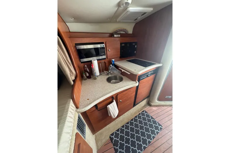 Slide: The Image of 2007 Rinker 320 Express Cruiser kitchen with microwave, sink, and stove. - 15