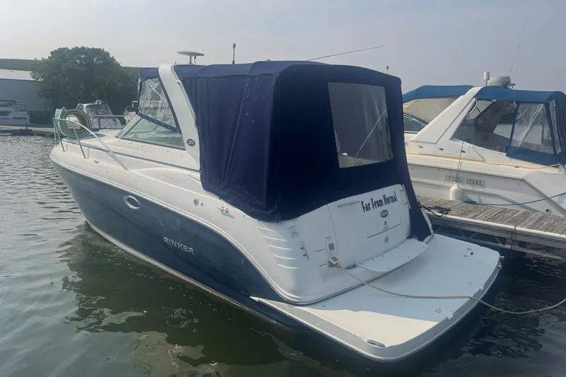 The Image of 2007 Rinker 320 Express Cruiser docked at marina, rear view with blue canopy. - 2