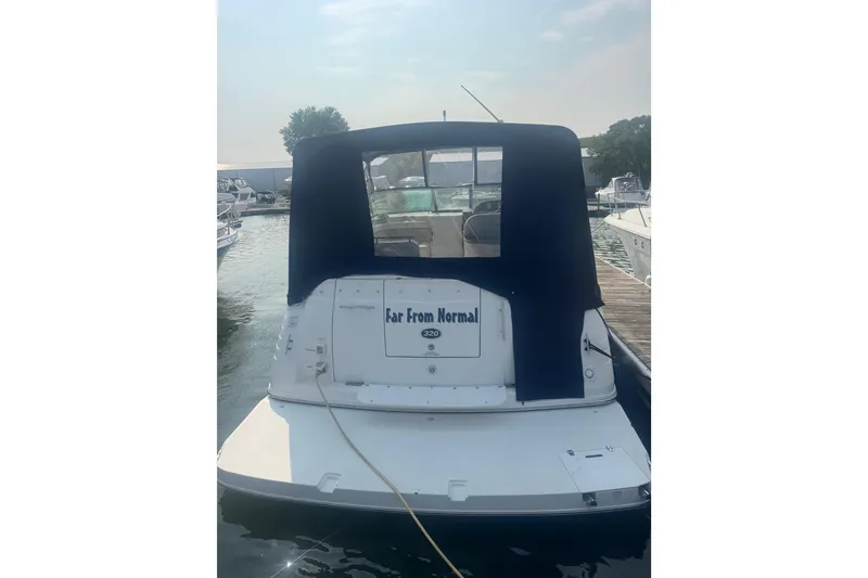 Slide: The Image of 2007 Rinker 320 Express Cruiser docked, rear view with canopy and "Far From Normal" text. - 24
