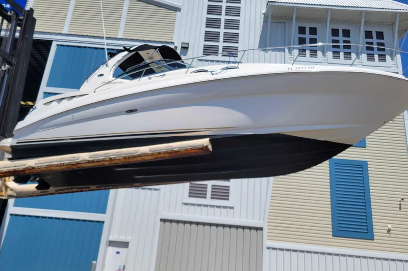Slide: The Image of 2003 Sea Ray 320 Sundancer boat lifted near a modern building. - 2
