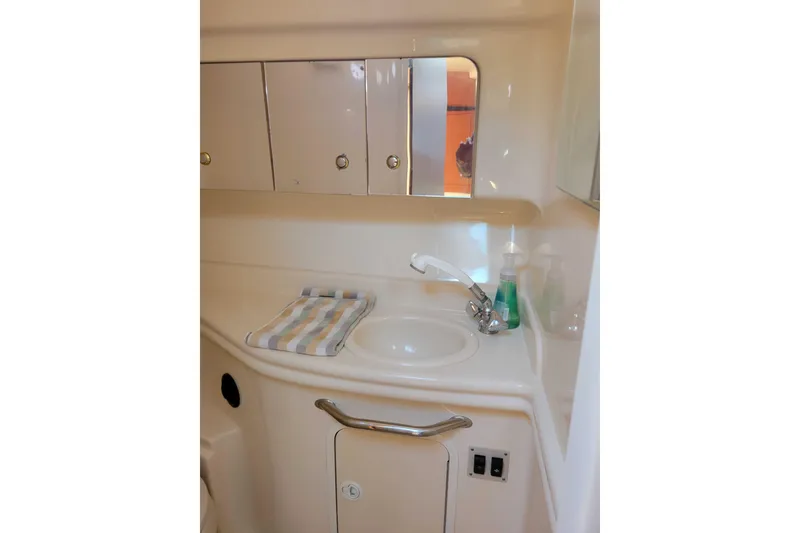Slide: The Image of 2003 Sea Ray 320 Sundancer bathroom with sink, mirror, and storage cabinets. - 23