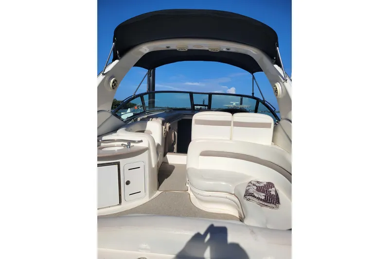 Slide: The Image of 2003 Sea Ray 320 Sundancer boat interior with seating and canopy under clear blue sky. - 9
