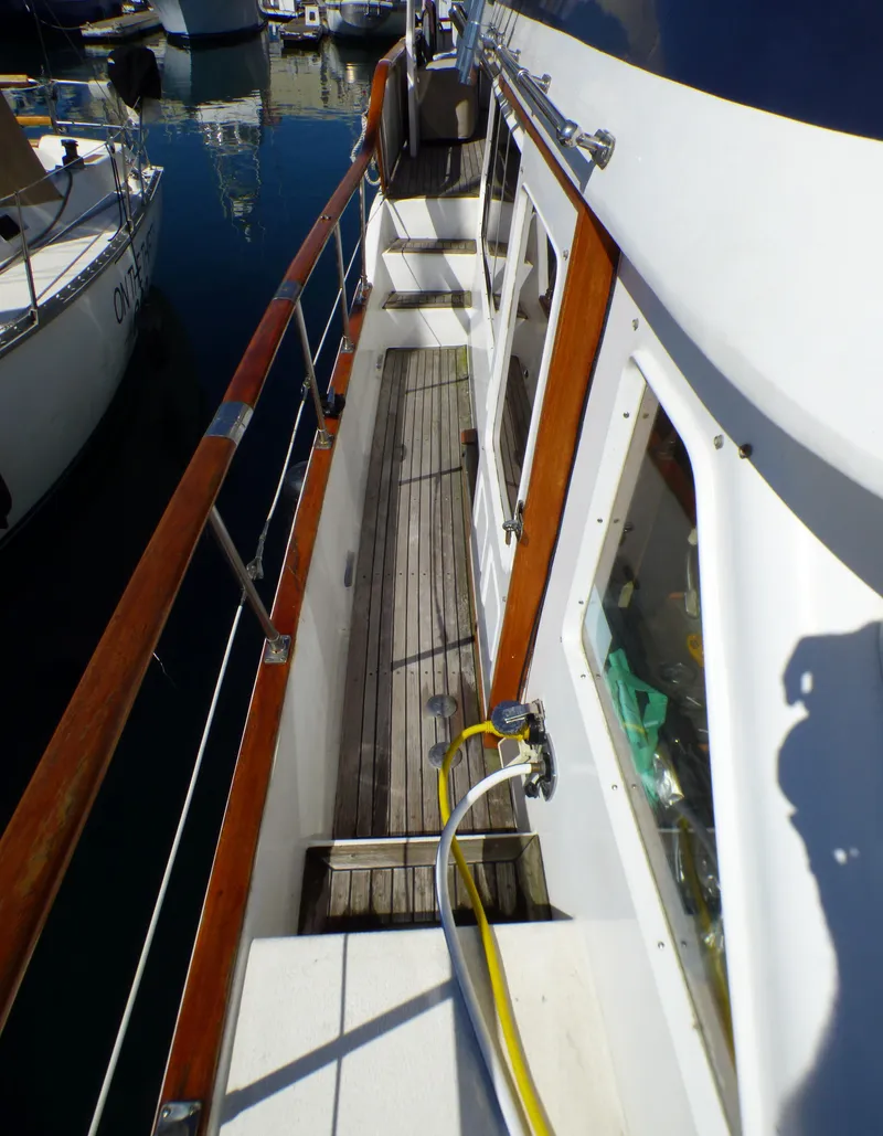 Slide: The Image of 1984 Spindrift 39 ft. Aft Cabin Twin Diesel yacht deck with wooden railings and docked boats. - 14