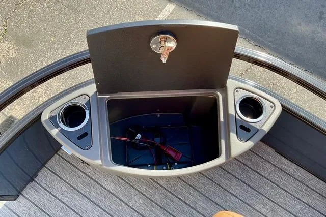 Slide: The Image of 2026 Ranger Reata 220F boat storage compartment with cup holders and key lock. - 10