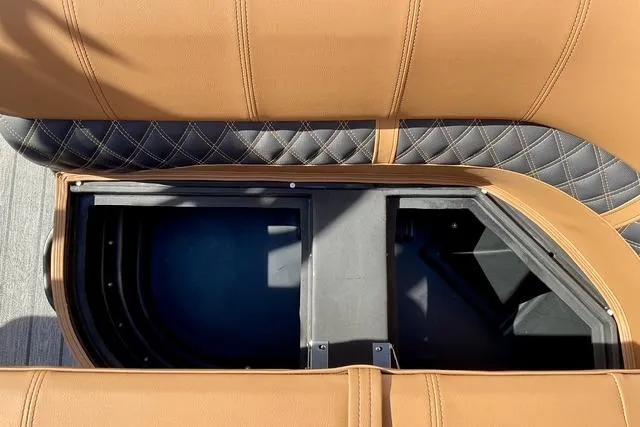 Slide: The Image of 2026 Ranger Reata 220F boat seat storage compartment with tan and black upholstery. - 13