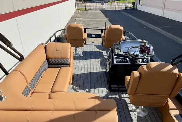 Slide: The Image of 2026 Ranger Reata 220F pontoon boat interior with tan seating and modern dashboard. - 16
